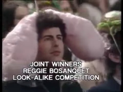 An audiene member from a sketch who's been roped into the events - a man has a massie fluffy pink cushion on his head, which enables him to be one of the joint winners of the Reggie Bosanquet Look-Alike Competition. The man is fairly young and looks nothing like the just-retired ITN newsreader. 